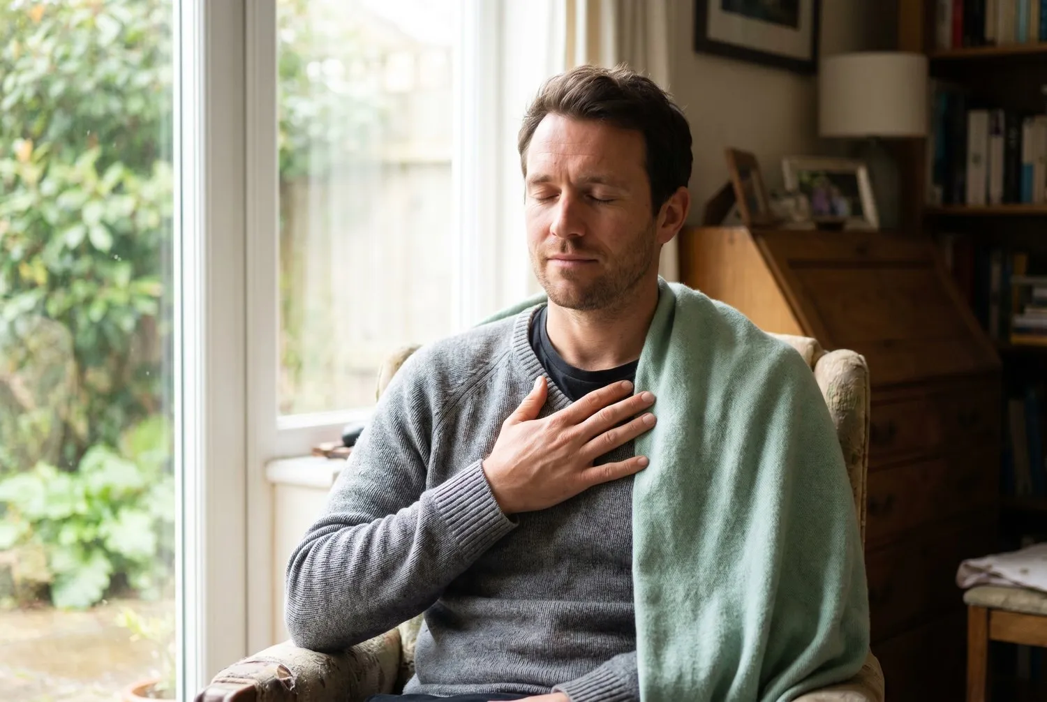 A man breathing calmly by a window after a wave of panic passes A man breathing calmly by a window after a wave of panic passes