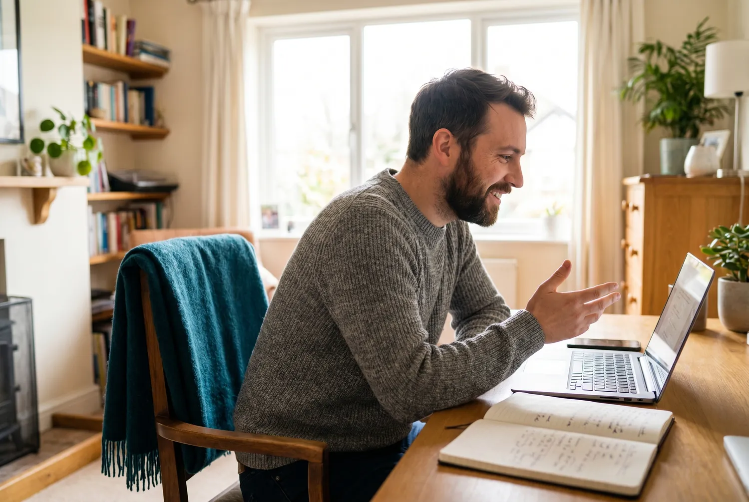 A man at a home desk in an attentive video conversation on a laptop